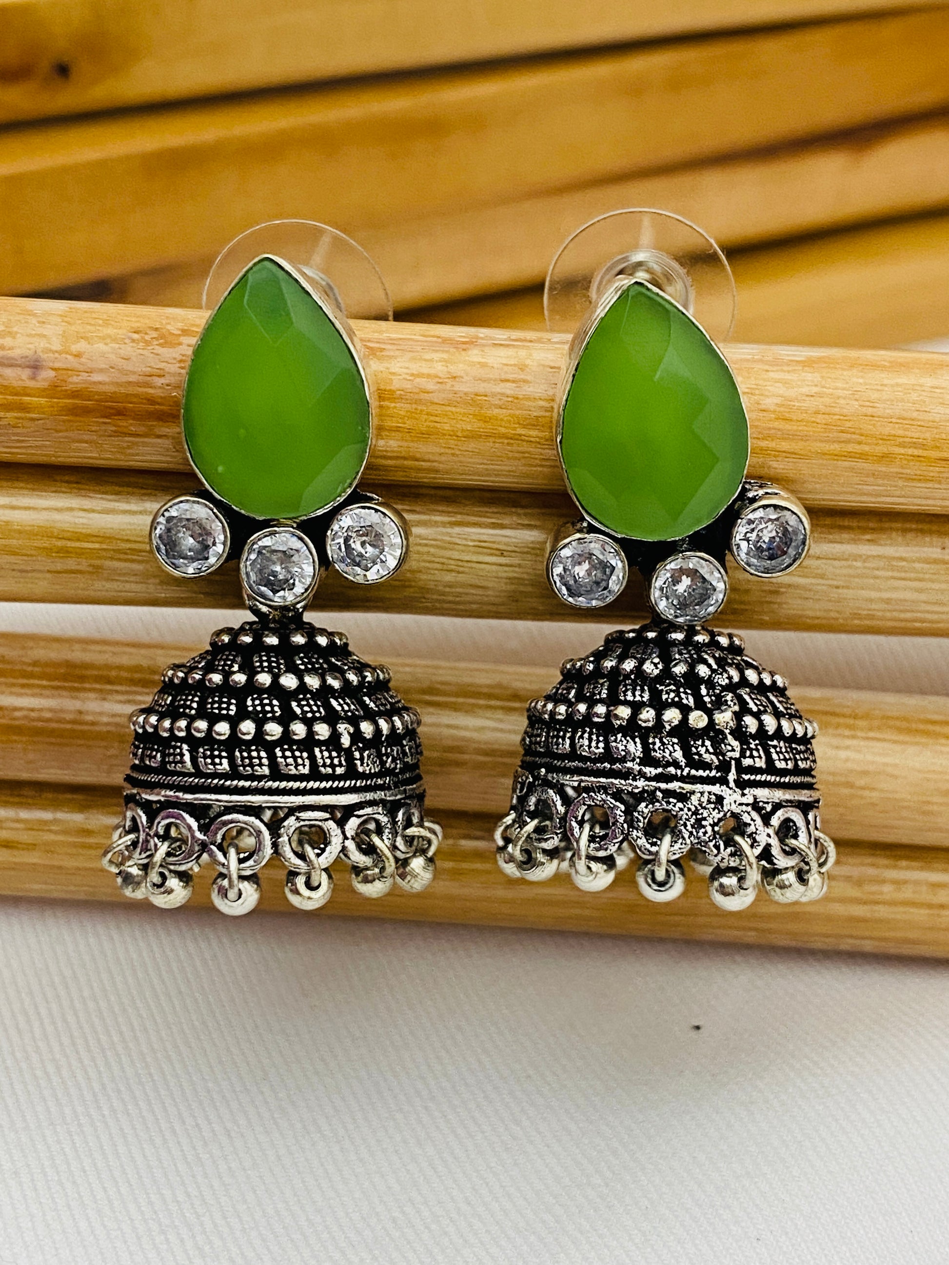 Lovely Green AD Stone Beaded Silver Toned Designer Jhumka Earrings With Black Pearl Drops