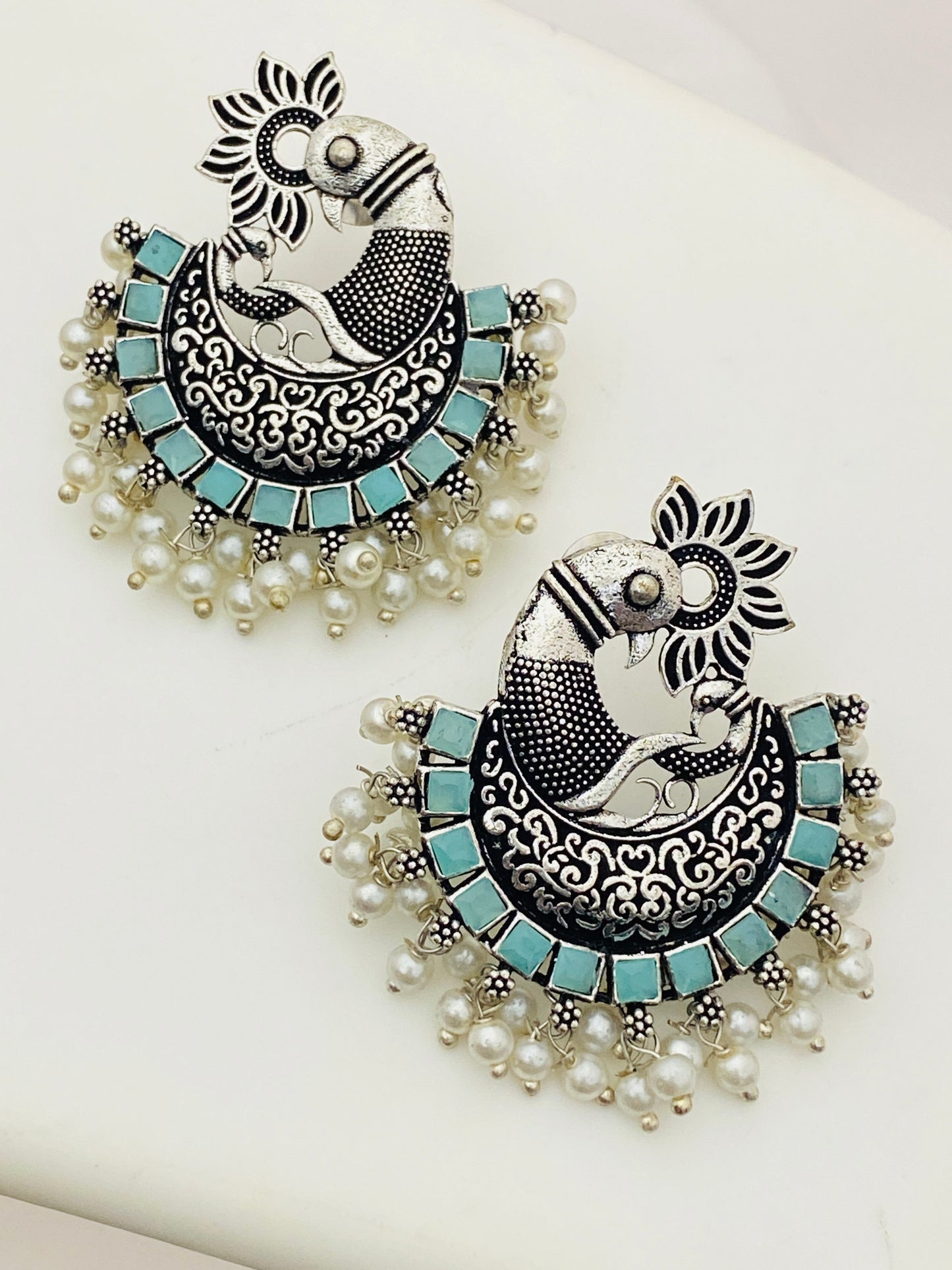 Alluring Sky Blue Stone Beaded Peacock Designed Silver Toned Oxidized Earrings With Pearl Drops