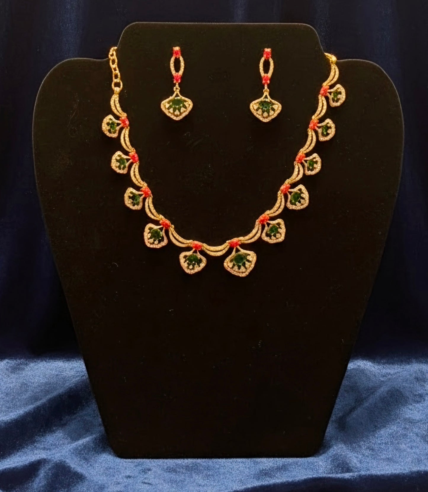 Pretty gold plated curved necklace set with green, red and white stones.